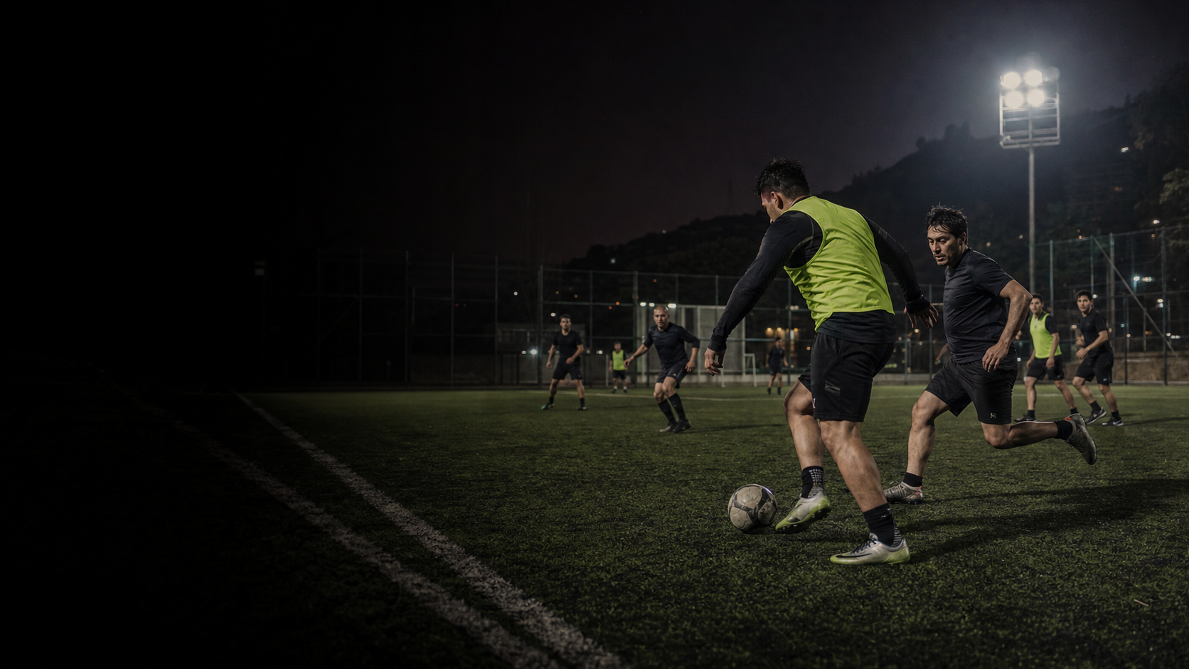 Partido de fútbol amateur adulto en cancha nocturna
